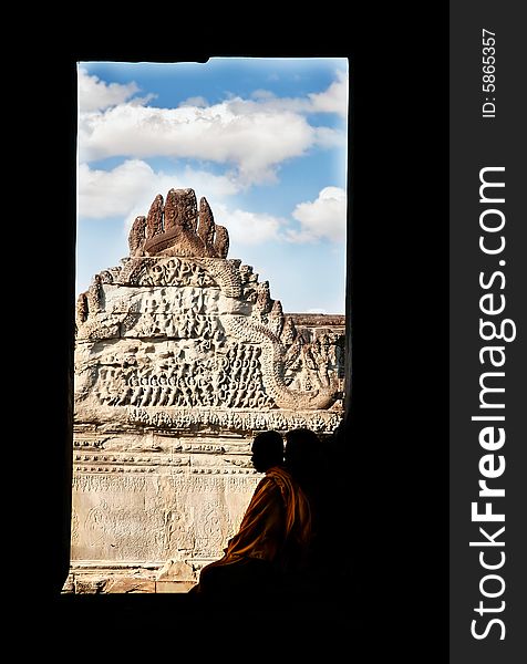 Silhoette of monk sitting in window frame on old temple background