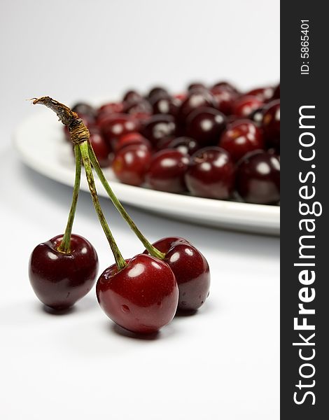 Three red cherries and cherries in white plate. Three red cherries and cherries in white plate