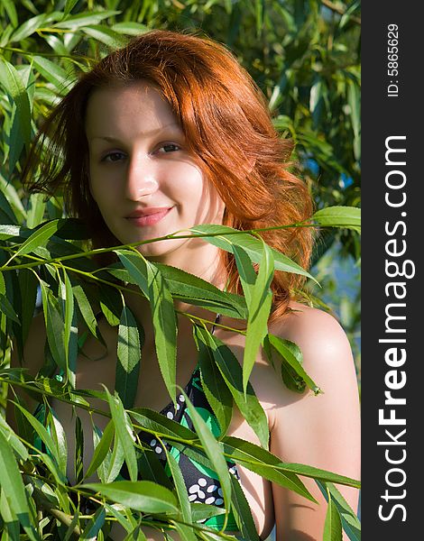 Portrait of the girl among green foliage