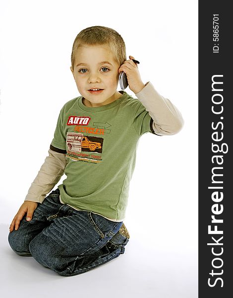Young boy in a green T-shirt kneeling pretending to be talking on a cell phone. Young boy in a green T-shirt kneeling pretending to be talking on a cell phone