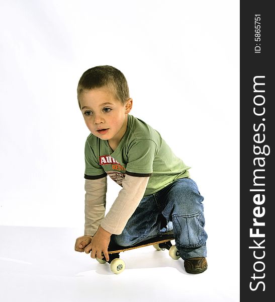 Young boy in a green T-shirt kneeling on a skate board. Young boy in a green T-shirt kneeling on a skate board