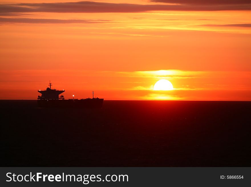 A sunrise on the open sea with ship in the background. A sunrise on the open sea with ship in the background
