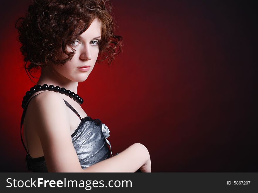 A beautiful curly redheaded girl is dressed in clothes, looks in a shot a quiet look. A beautiful curly redheaded girl is dressed in clothes, looks in a shot a quiet look