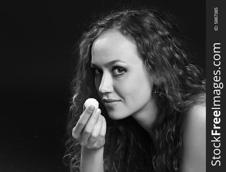 A young girl holds the unfolded white candy in a hand. A young girl holds the unfolded white candy in a hand