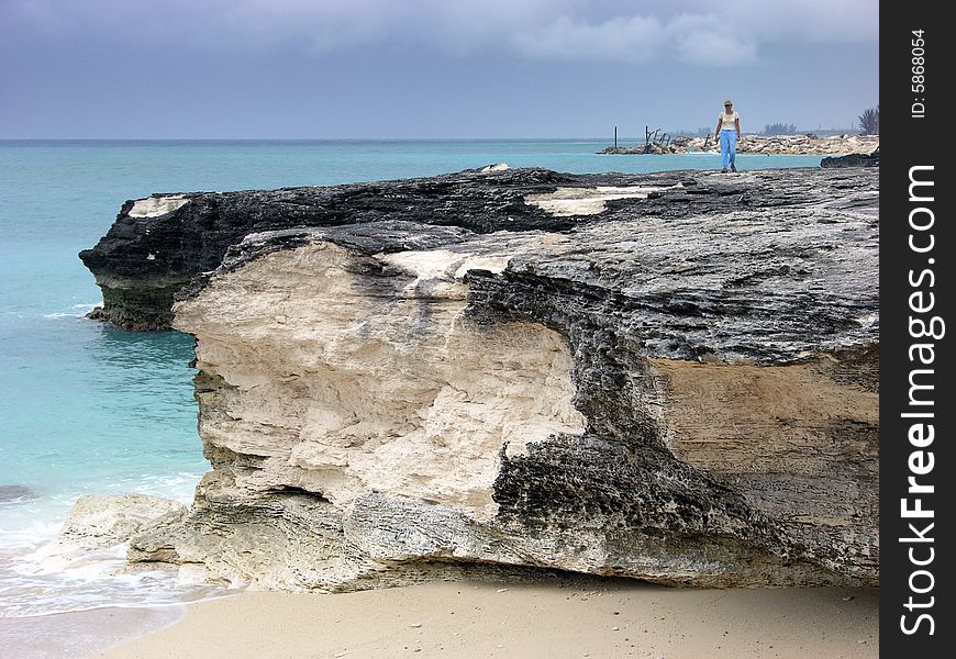 The girl walking on a rocky, eroded beach in Freeport on Grand Bahama Island, The Bahamas. The girl walking on a rocky, eroded beach in Freeport on Grand Bahama Island, The Bahamas.