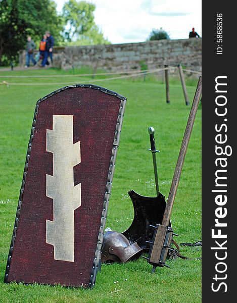 Different weapons lying on a grass: sword club helmet shield. Different weapons lying on a grass: sword club helmet shield