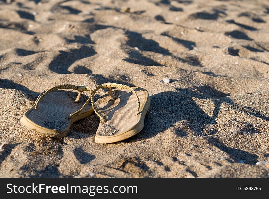 Image of a pair of beach shoes lying on the sand. Image of a pair of beach shoes lying on the sand