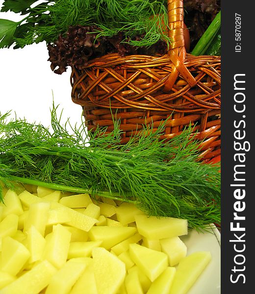 Vegetables placed in wicker basket and a plate with cut potatoes. Vegetables placed in wicker basket and a plate with cut potatoes