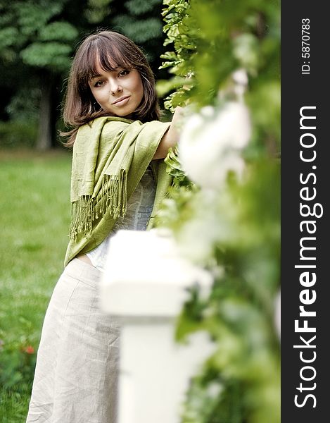 The beautiful young woman standing near the wicker fence