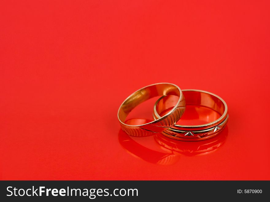 Gold wedding rings on red background