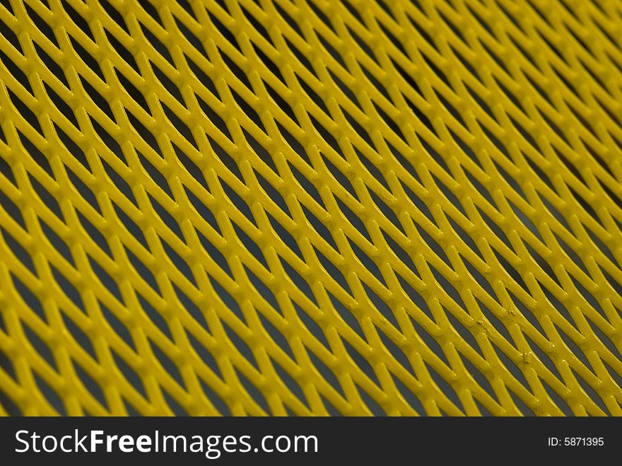 Abstract of yellow, painted metal grid. Shallow depth of field with the center part sharply in focus. Abstract of yellow, painted metal grid. Shallow depth of field with the center part sharply in focus.