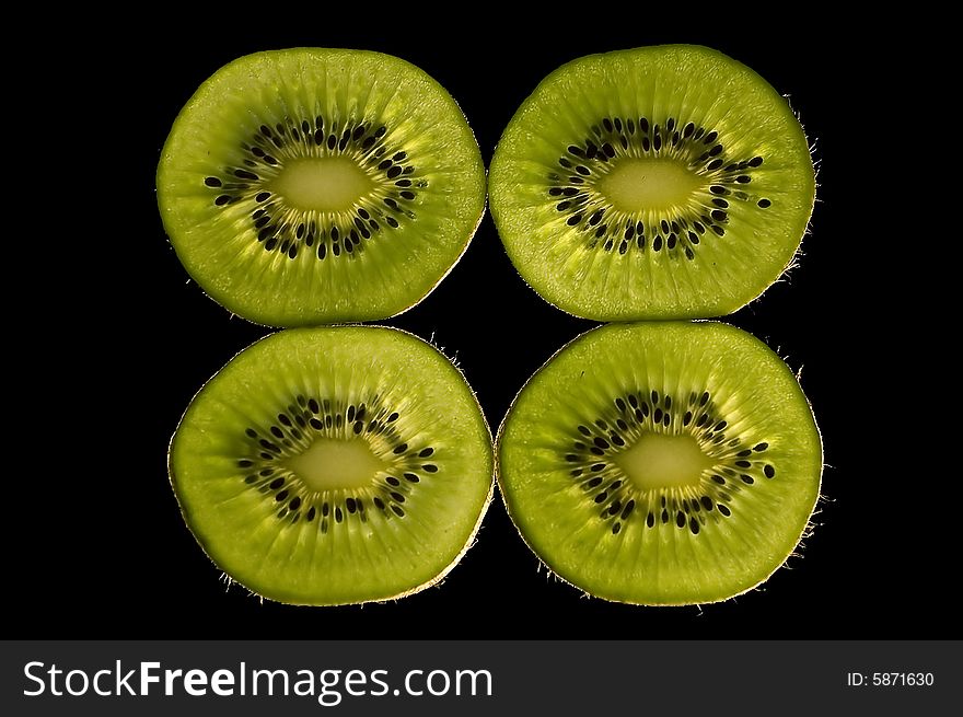 Four slices of kiwi fruit at dark background. Four slices of kiwi fruit at dark background