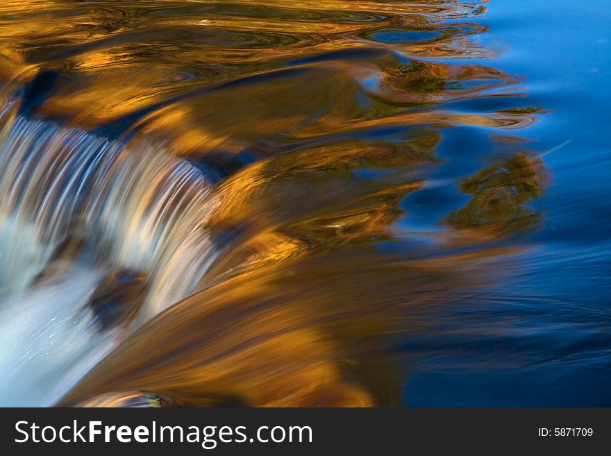 Closeup of small waterfall with golden reflections. Closeup of small waterfall with golden reflections.