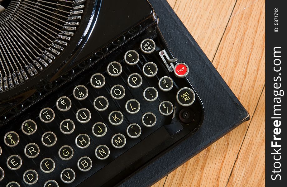 Partial view of a vintage portable typewriter on wood floor. Partial view of a vintage portable typewriter on wood floor.