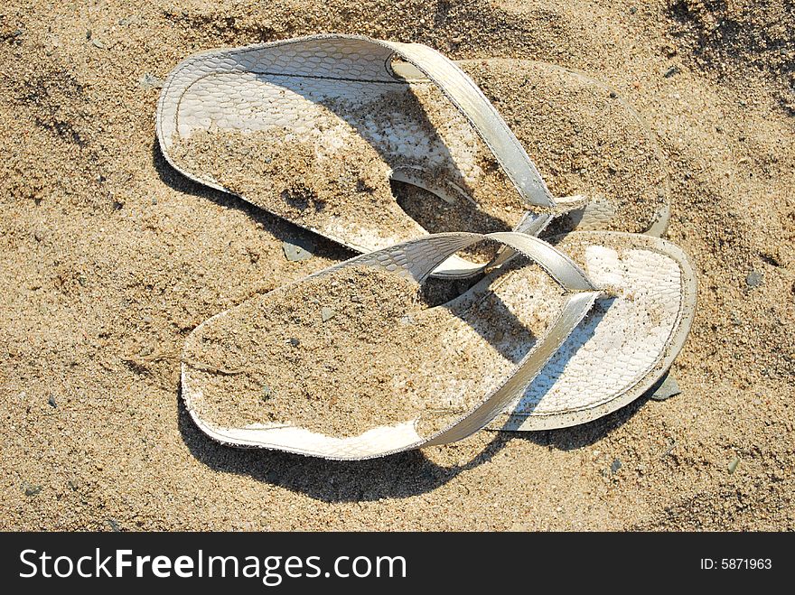 Sandals on the hot sand. Sandals on the hot sand