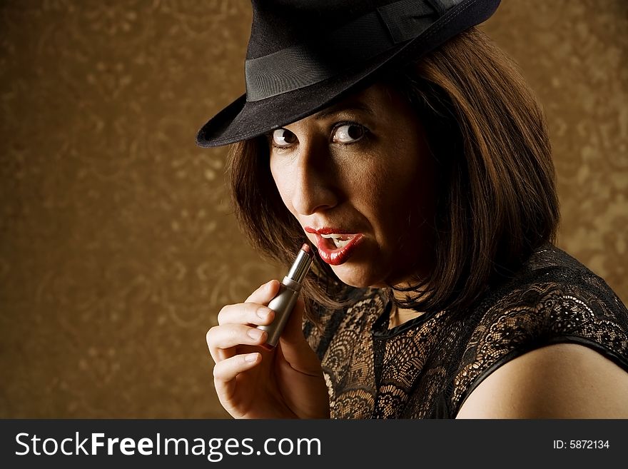 Pretty Hispanic Woman in a Fedora Applying Lipstick. Pretty Hispanic Woman in a Fedora Applying Lipstick