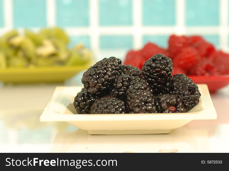Blackberries against blur raspberries and kiwi background. Blackberries against blur raspberries and kiwi background