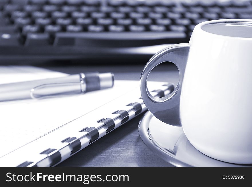 Cup of coffee, keyboard, pen and notebook on a table. Cup of coffee, keyboard, pen and notebook on a table