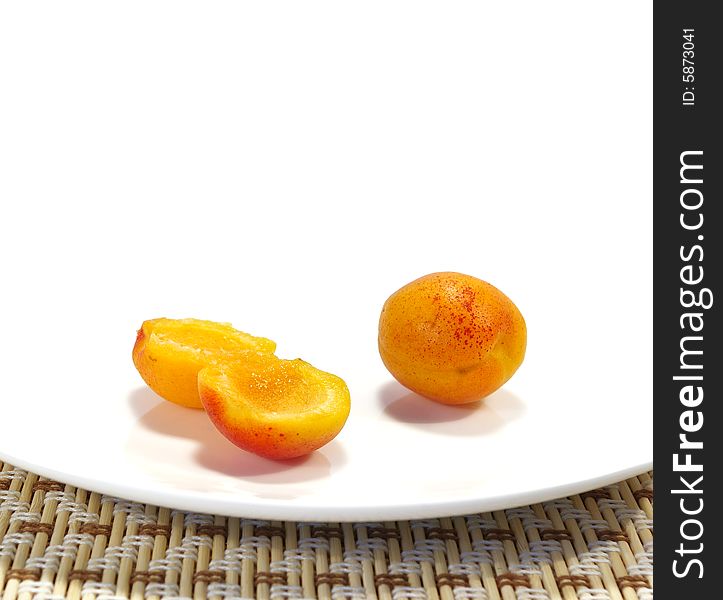 Ripe sweet apricots on a white plate