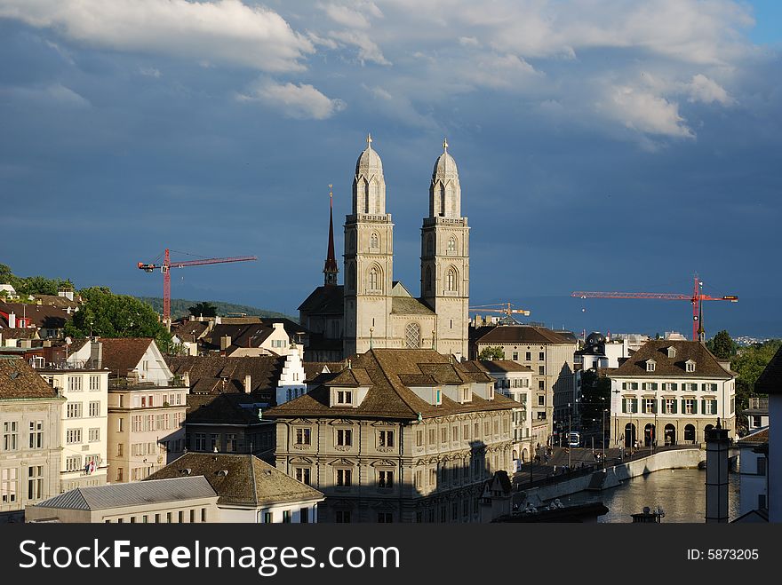 Zurich's Cathedral near the bank of Limmat river surrounded by building cranes
