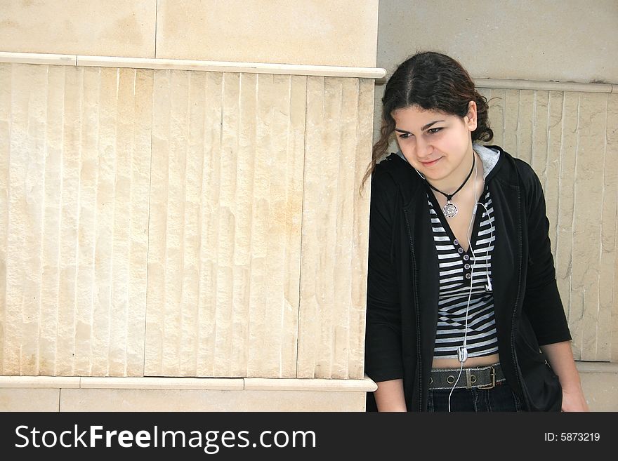 Pretty girl with ear-phones at the wall.