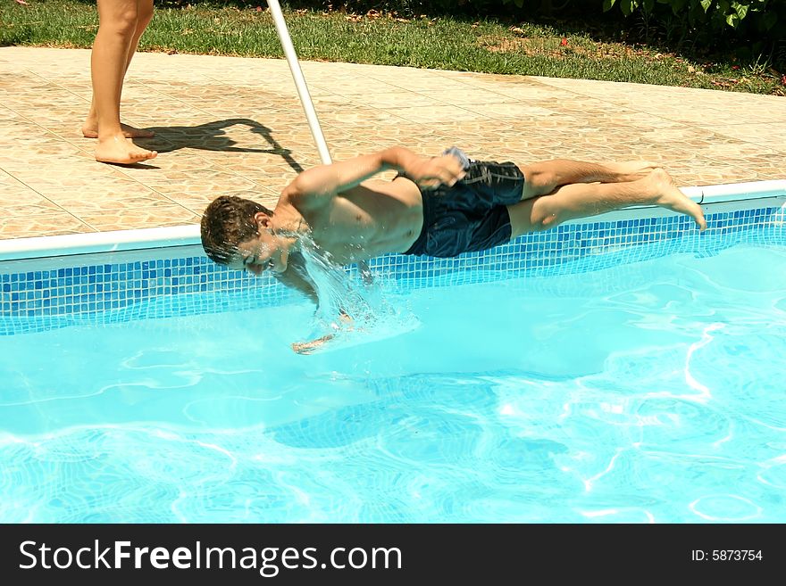 Cheerful teen falling into the swimming pool.