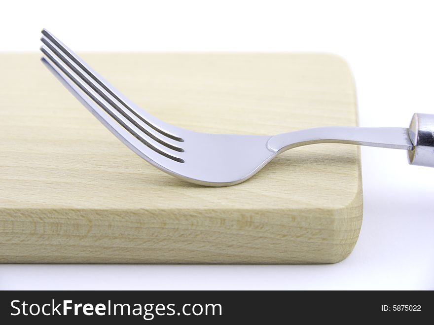 Metal fork and wooden board on white background