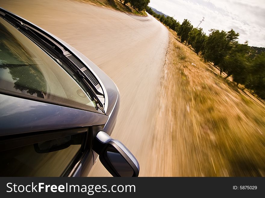 Cruising the countryside in a blue car at high speed.