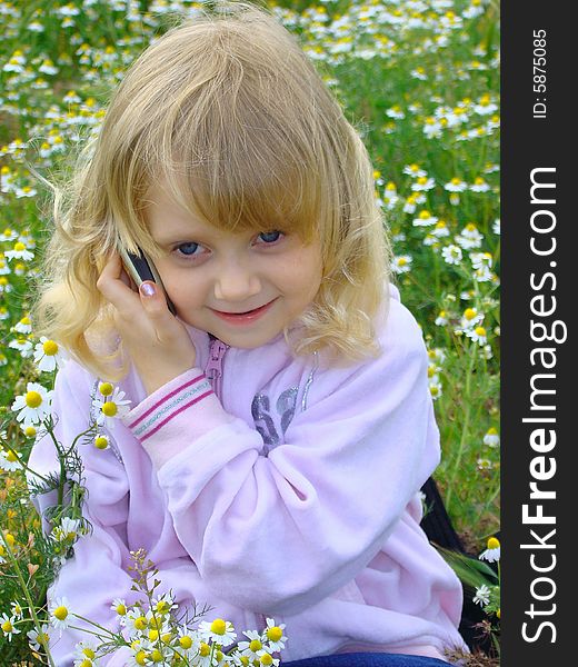 Little girl in tender-lilac clothes communicates by a mobile telephone. Little girl in tender-lilac clothes communicates by a mobile telephone.