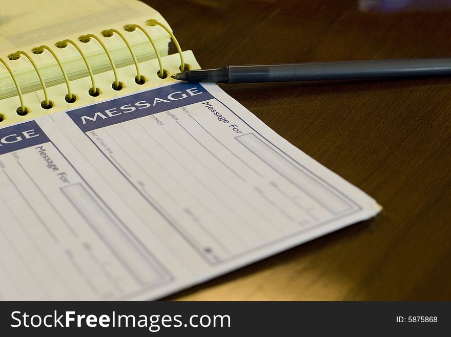 Spiral yellow notepad and black pen on a wooden table. Spiral yellow notepad and black pen on a wooden table.