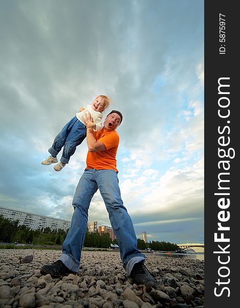 Father and child outdoor on stones and river