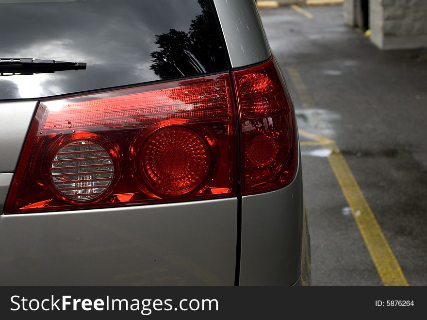 Close up of a red passenger side tail light on a parked silver car. Close up of a red passenger side tail light on a parked silver car.