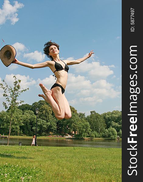 The sports beauty girl in bikini jumps above a lawn. The sports beauty girl in bikini jumps above a lawn