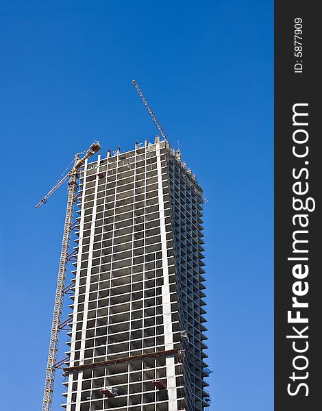 Cranes and building on a background blue sky. Cranes and building on a background blue sky