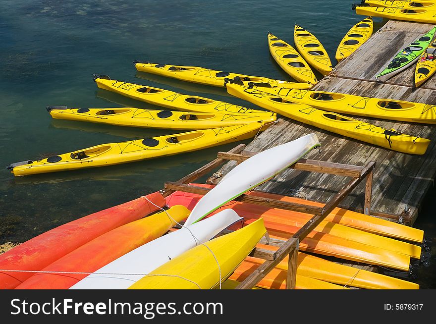 A large group of yellow, two-person kayaks tied to a wharf. A large group of yellow, two-person kayaks tied to a wharf.