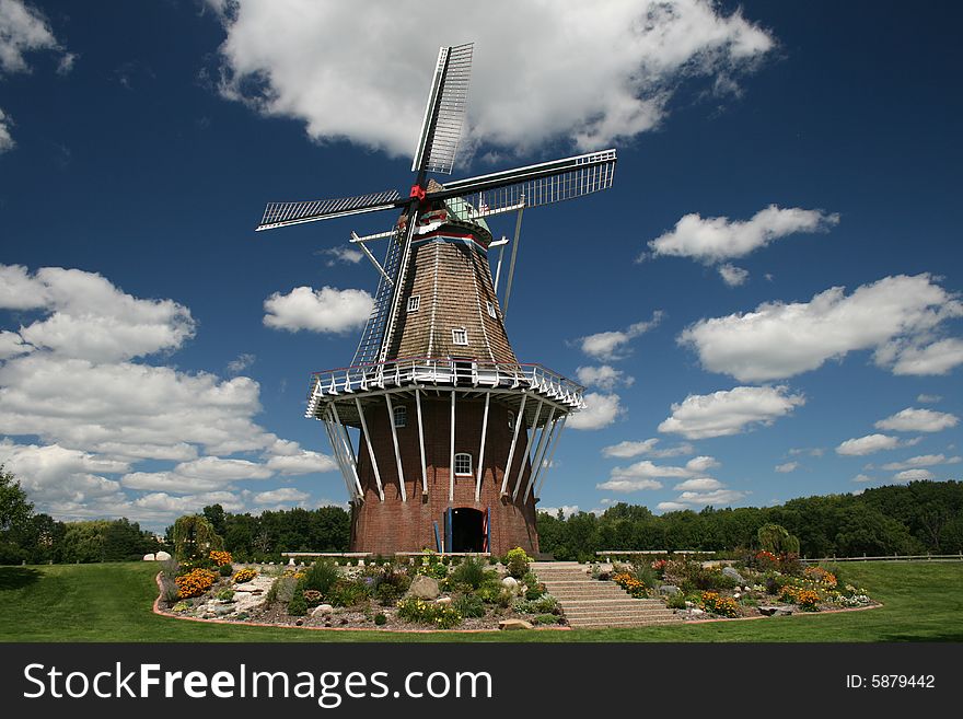 An image of an old Dutch windmill against a blue sky and white clouds
