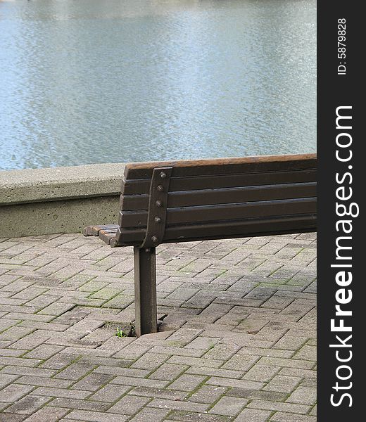 A brown park bench by the water