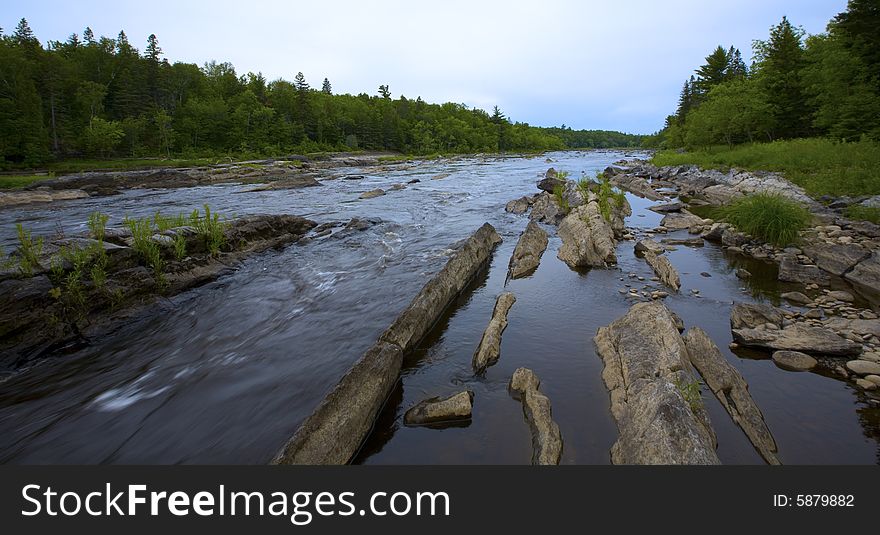 Looking upstream as a river rushes through stone  in the North Woods of Minnesota.