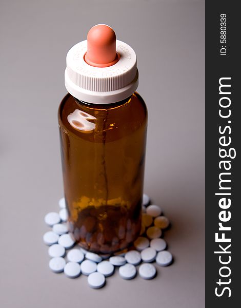 The medicine bottle is surrounded by tablets. The medicine bottle is surrounded by tablets