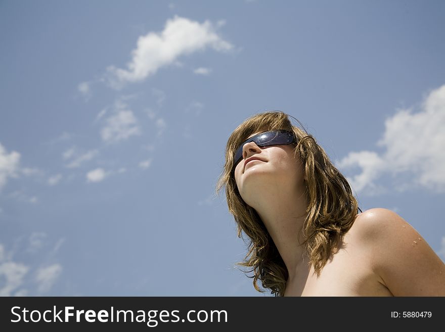 Teen girl with sunglasses blue sky and clouds on backkground