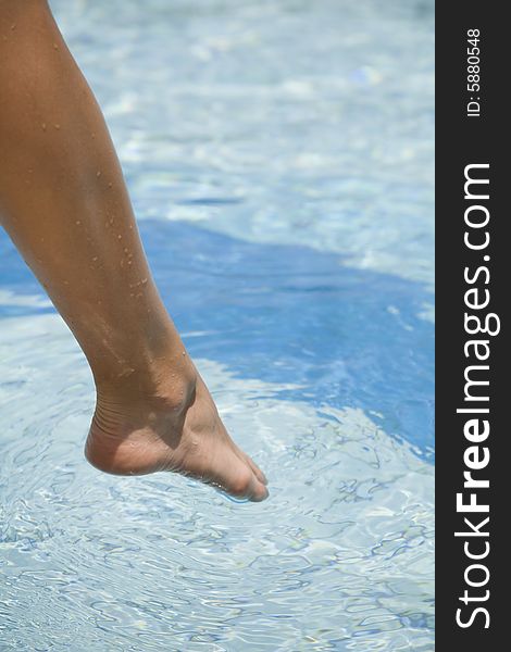 Feet step into the clear water swimming pool. Feet step into the clear water swimming pool