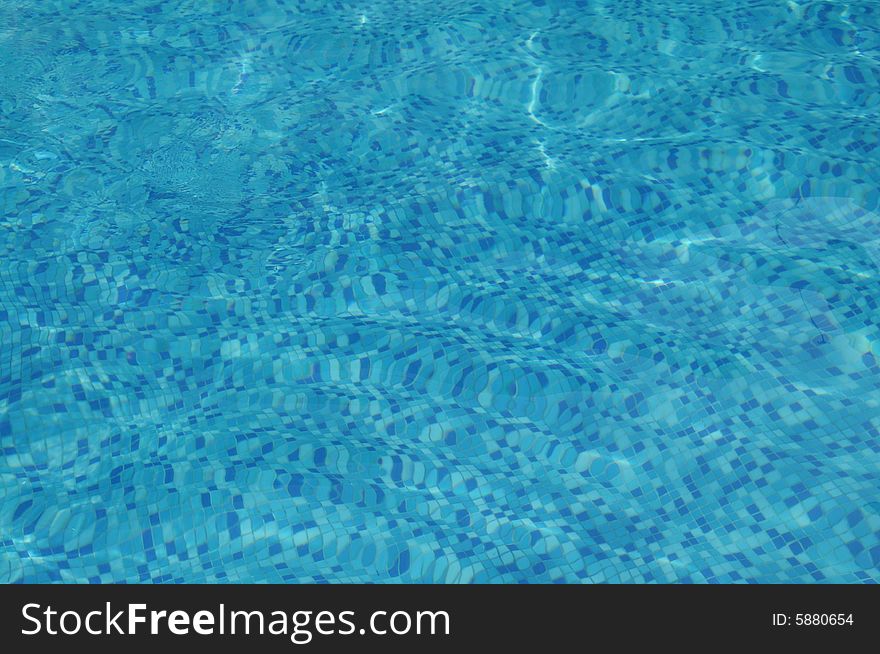 The blue clear water and mosaic in the swimming pool background. The blue clear water and mosaic in the swimming pool background.