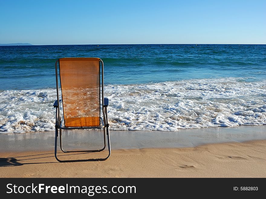 Lonely armchair waits for the tourist on coast of ocean