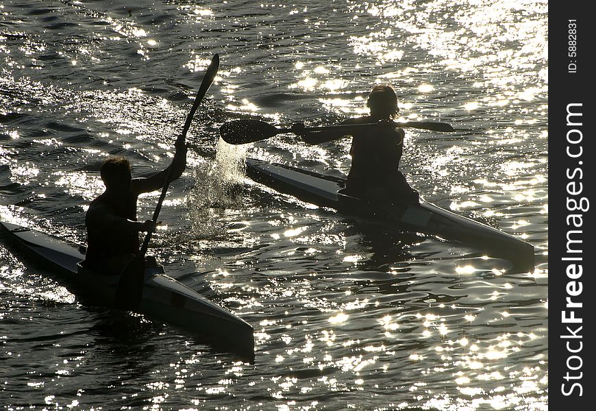 Two rowers in their's canoes on the Arno river at the sunset hour