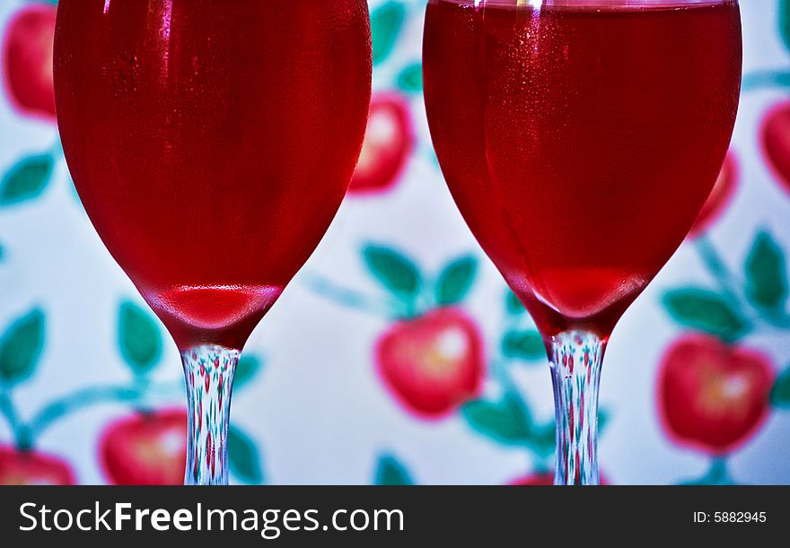 Two cold red drinks in wine glasses. Decorative wallpaper background. Two cold red drinks in wine glasses. Decorative wallpaper background.