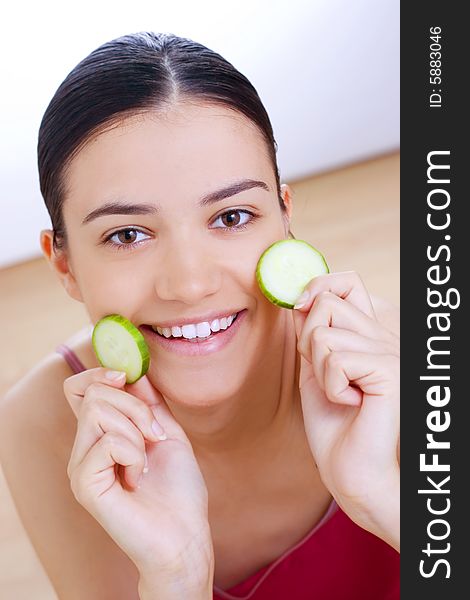 Young smiling woman holding cucumber close her face