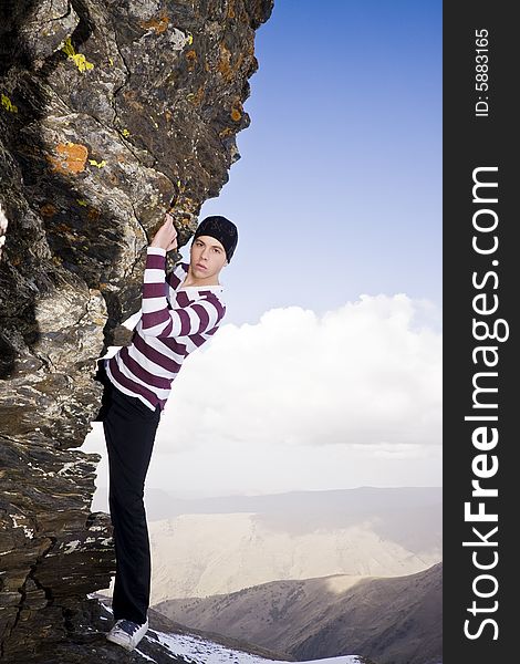Young model climbing a small cliff at high altitude in casual clothes. Young model climbing a small cliff at high altitude in casual clothes.
