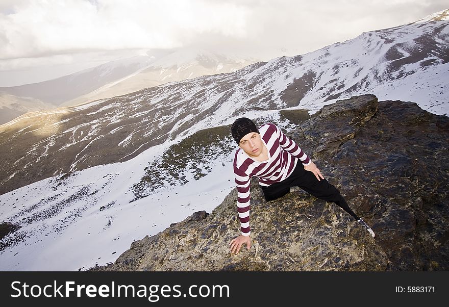 Young man posing at high altitude after climbing a cliff. Young man posing at high altitude after climbing a cliff