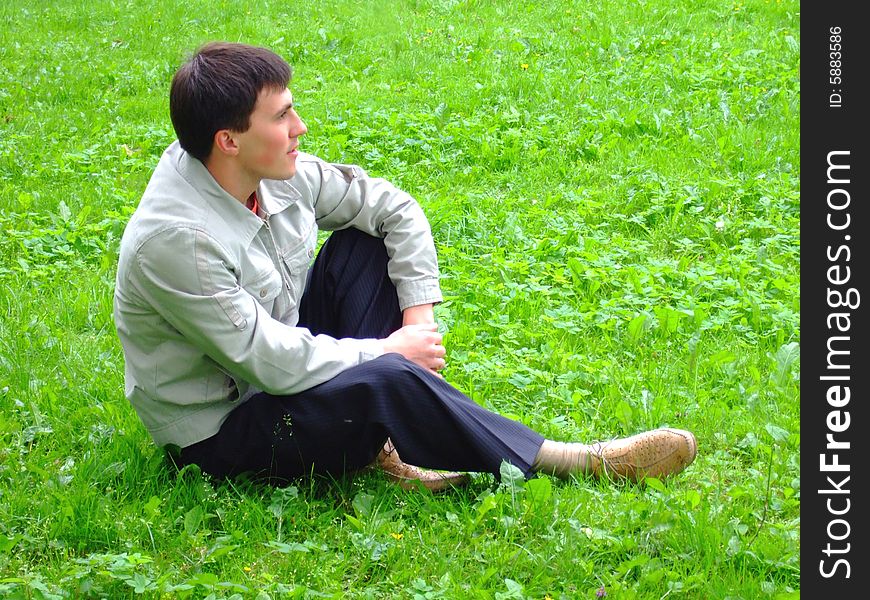 Thoughtful young man on a grass.