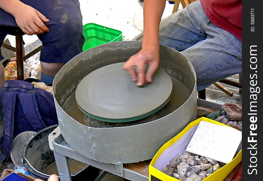 The man polishing stones - agates. Close up of the hand keeping small agate on the grinder. The man polishing stones - agates. Close up of the hand keeping small agate on the grinder.